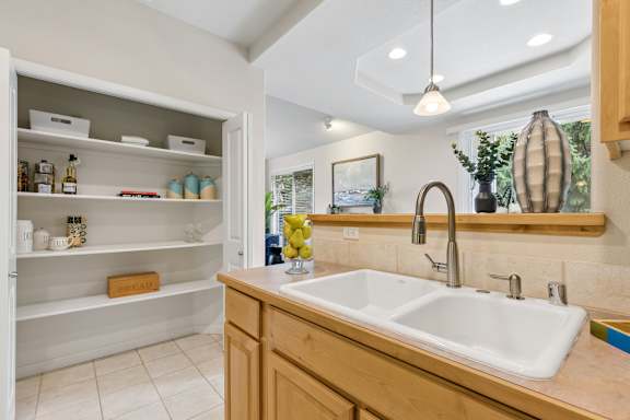 A kitchen with a sink, a cabinet, and a window.