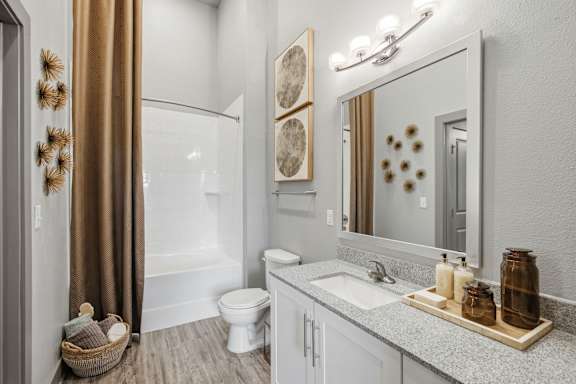 A bathroom with a white toilet, a sink, a mirror, and a shower.