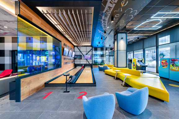 a bowling alley in the lobby of a building with blue and yellow couches