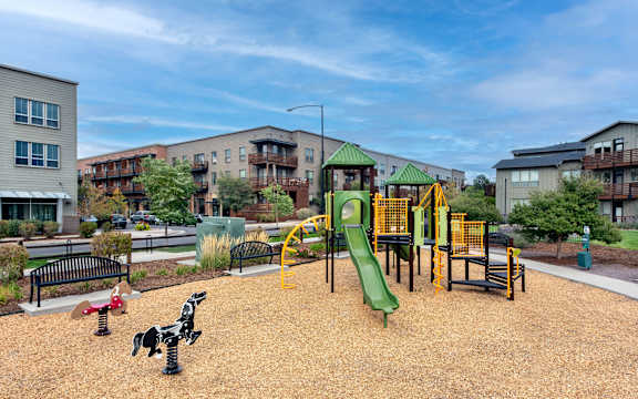 A playground with a green slide and a yellow and black play structure.