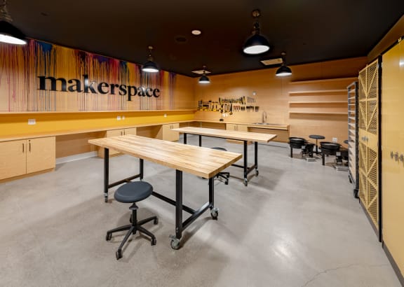 a communal table in a maker space with desks and chairs