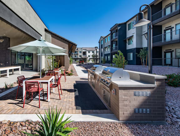 an outdoor patio with a barbecue grill and a table with chairs