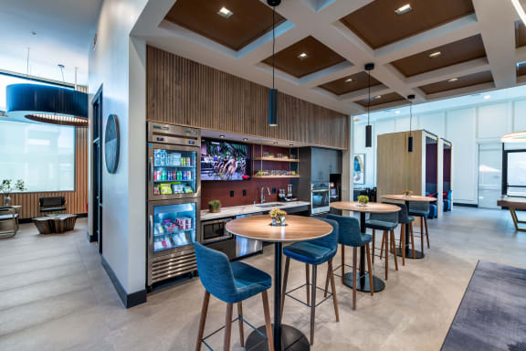 a lobby with tables and chairs and a bar with a television