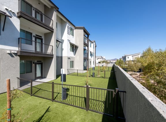 a view of an apartment complex with a green lawn and a fence