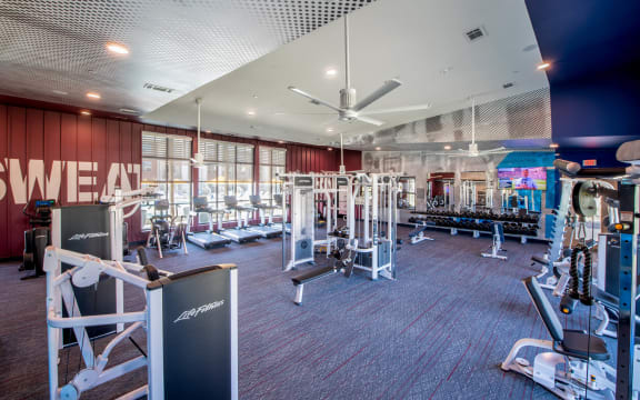 a gym with weights and cardio equipment and a sign on the wall