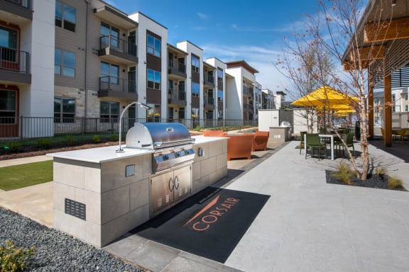 an outdoor entertaining area with a grill in front of an apartment building