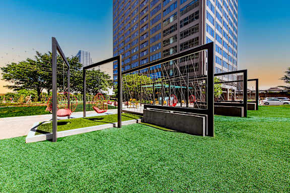 A playground with a swing set and a tall building in the background.