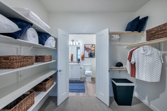a walk in closet with shelves and wicker baskets and a bathroom with a toilet