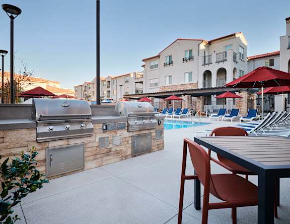 A patio with a grill and chairs is set up.