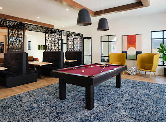 A pool table is in the middle of a room with a blue rug.