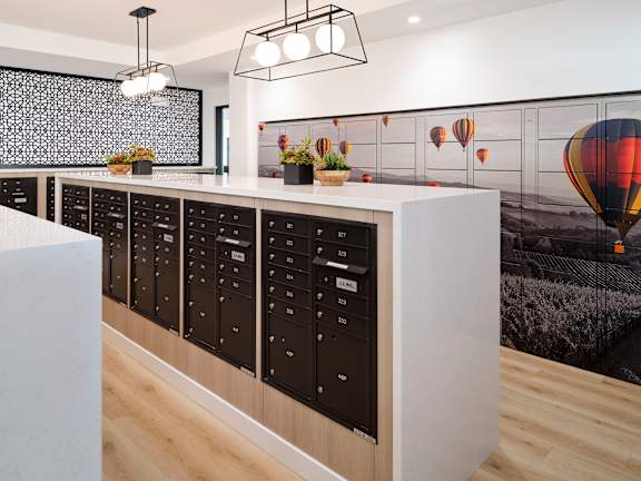 A modern kitchen with a long counter and a wall mural of hot air balloons.