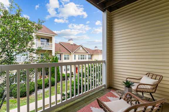 A balcony with a chair and a table overlooking a residential area.