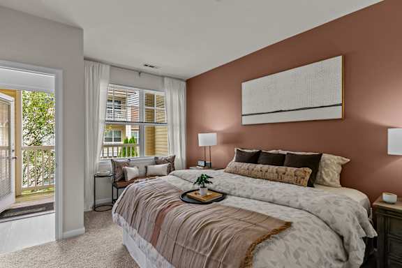 A bedroom with a large bed and a window overlooking a balcony.