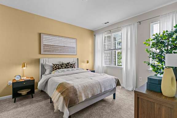 A bedroom with a bed, nightstand, and window.