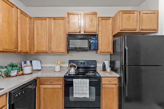 A kitchen with wooden cabinets and black appliances.