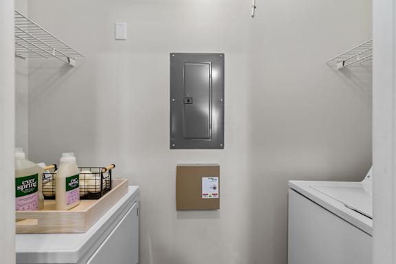 A small room with a metal shelf and a brown box on the wall.