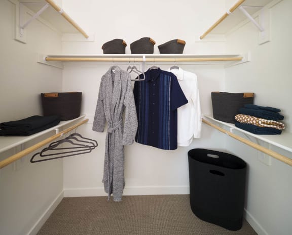 a walk in closet with wooden shelves and racks with clothes and baskets