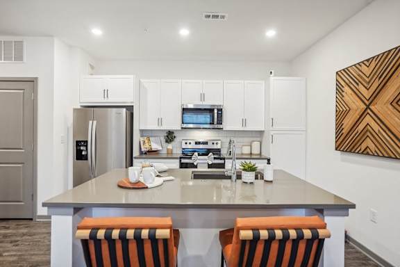 A kitchen with a refrigerator, microwave, oven, and sink.
