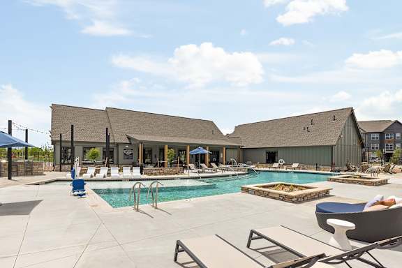 A large outdoor swimming pool with lounge chairs and a building in the background.