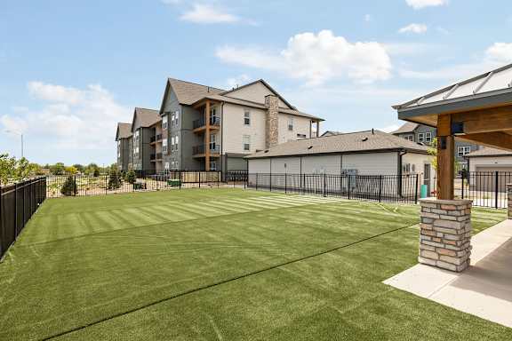 A large grassy area in front of a building with a fence on the left side.
