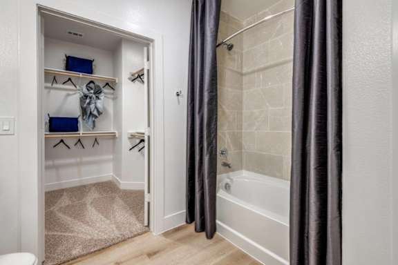A bathroom with a white tub and a white door with a towel hanging on it.