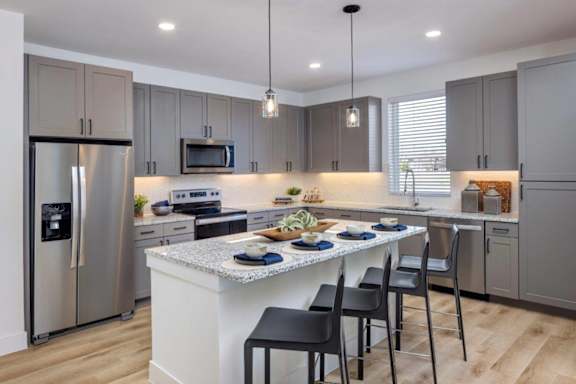A modern kitchen with a center island and stainless steel appliances.