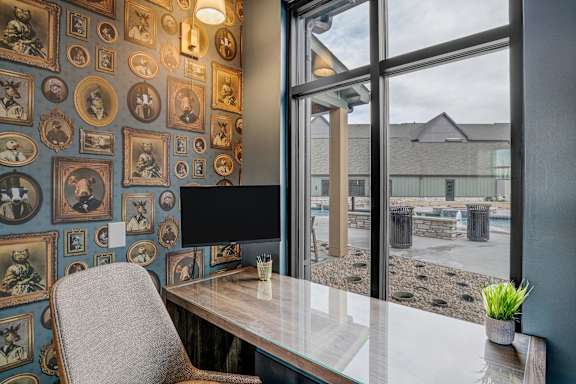 A room with a desk, chair, and a wall of framed pictures.