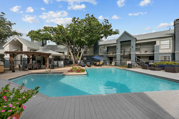 A large swimming pool surrounded by a wooden deck and a building in the background.