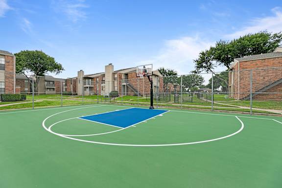 A basketball court with a blue half court in the middle.