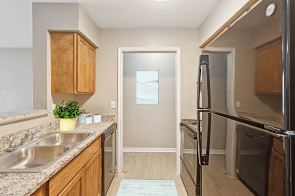 A kitchen with a sink, refrigerator, and wooden cabinets.