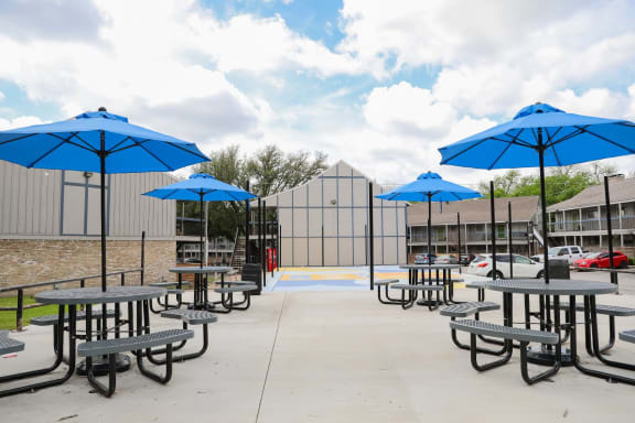 a picnic area with tables and umbrellas in front of a building at Aero White Rock, Dallas, 75238