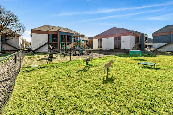 A green lawn with a fence and a playground.