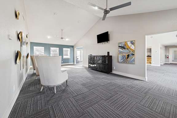 A living room with a grey carpet and a white chair.