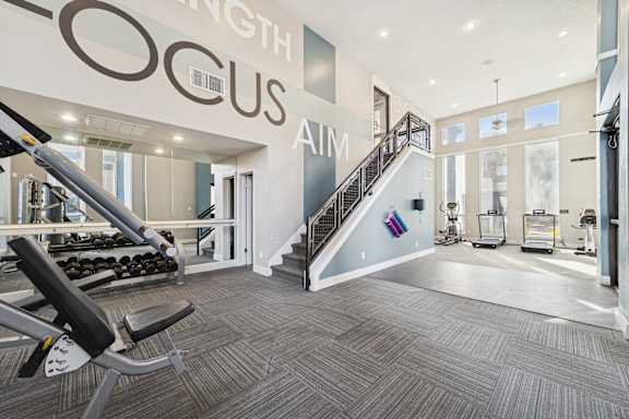 A gym with a staircase and a weight machine.