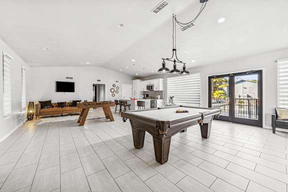 A billiard table is in the middle of a white tiled room.