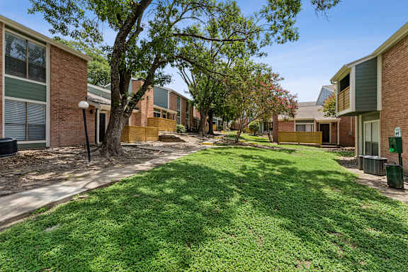 Walkway through courtyard with large shade trees at Knoll Crest Apartments, San Antonio, TX