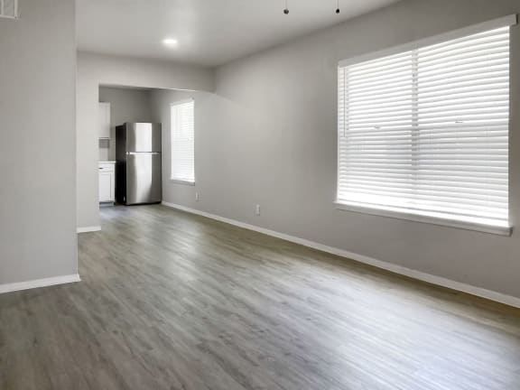 an empty living room with a large window and a white refrigerator  at Sunset Heights, San Antonio