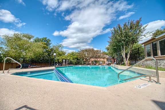 A swimming pool surrounded by trees and a clear blue sky.