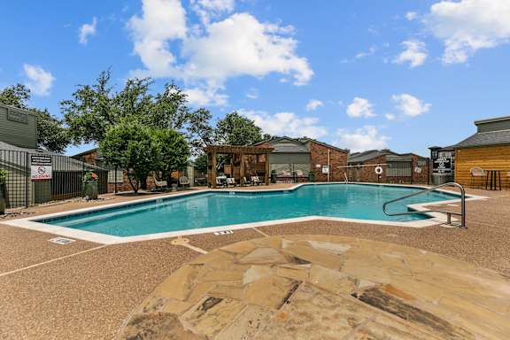 A large outdoor swimming pool surrounded by a stone patio.