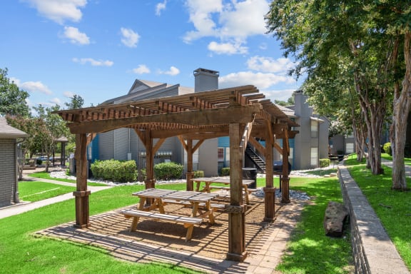 a wooden pergola with a picnic table in the middle of a grassy area  at Vesper, Dallas, TX