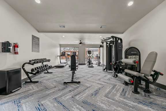 A gym with a variety of equipment including treadmills, weights, and exercise machines.