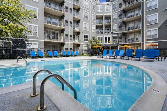A swimming pool in front of a multi-story apartment building.