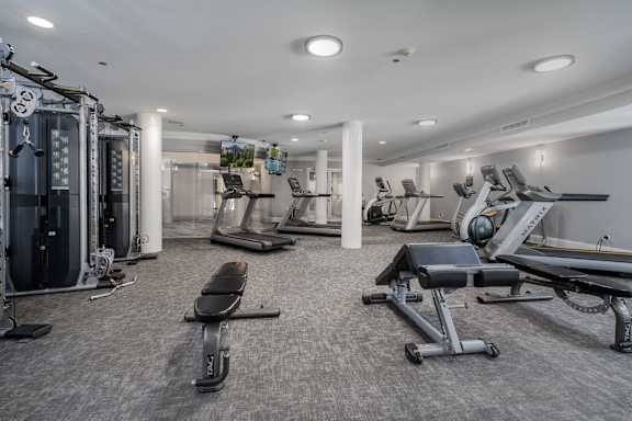 A spacious gym with a variety of equipment including treadmills, stationary bikes, and weight machines.