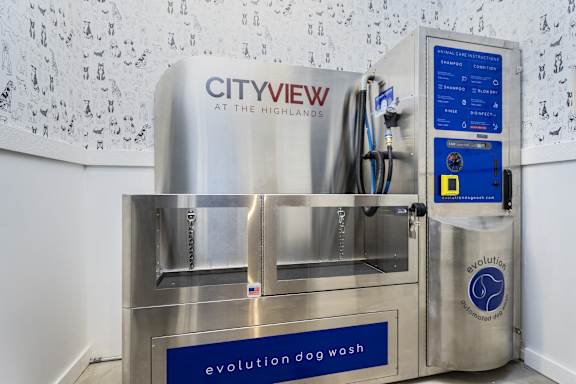 A machine with a blue label that says "evolution dog wash" is in front of a wall with a pattern of dog paw prints.