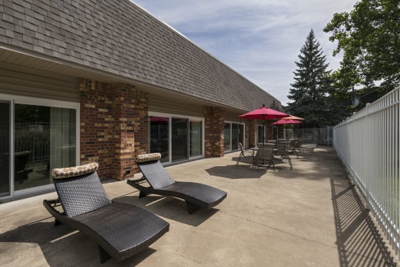 a patio with chairs and umbrellas in front of a building