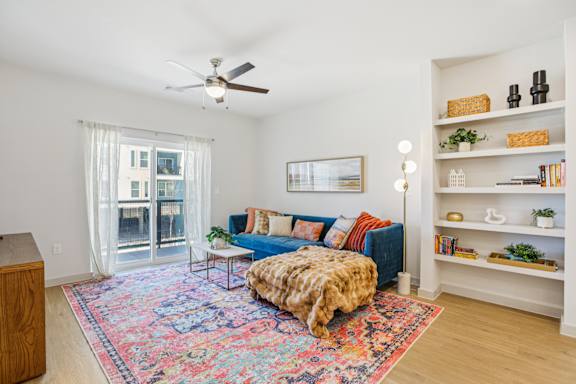 A living room with a blue couch and a colorful rug. at ThreeTwenty at the Vybe Apartments, Texas, 78640