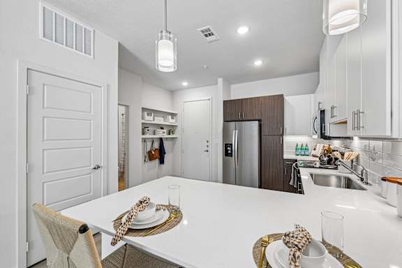 A modern kitchen with a dining table set for two.