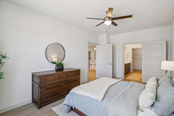 A bedroom with a bed, dresser, and mirror. at ThreeTwenty at the Vybe Apartments, Kyle, TX