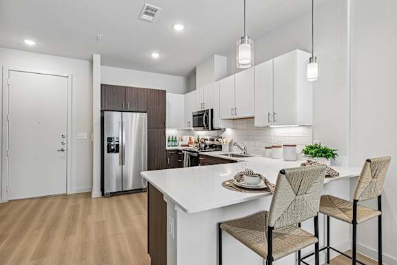 A kitchen with a white countertop and brown chairs.