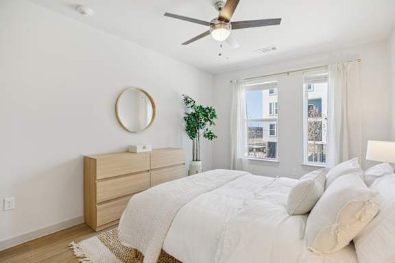A bedroom with a bed, dresser, and window. at ThreeTwenty at the Vybe Apartments, Kyle